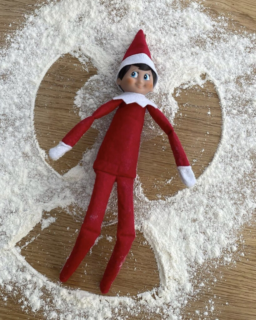 Elf makes a snow angel out of flour