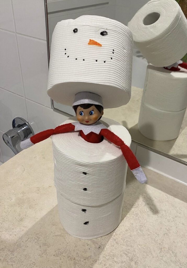 Elf hiding in a toilet paper snowman